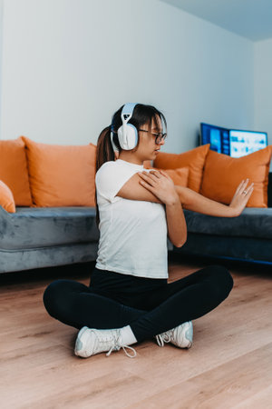 A woman stretching in her apartment during early morning after training , reflecting her dedication to a healthy lifestyle. This moment highlights the importance of regular exercise and self-care, even in the comfort of ones own homeの写真素材