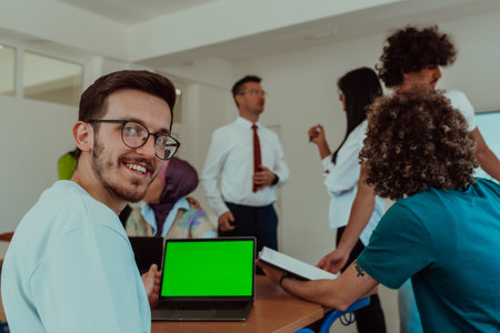 A group of business colleagues exchange knowledge and insights while utilizing laptops in the office, showcasing collaborative learning, effective communication, and a dynamic corporate environmentの写真素材