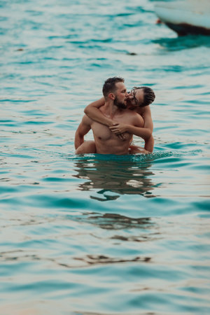 A romantic young couple sharing a passionate kiss amidst the serene beauty of the ocean at sunset.の写真素材