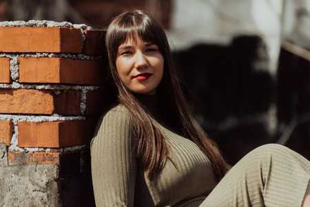 A confident and stylish plus-size woman walking by a modern building in an olive green dress, radiating beauty, empowerment, and self-love.の写真素材
