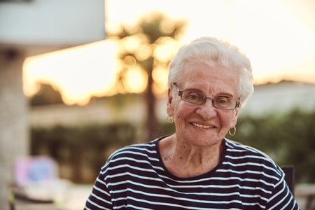Unfiltered portrait, a real elderly woman sits gracefully in a chair, showcasing the authenticity of aging with wrinkles and a natural faceの写真素材
