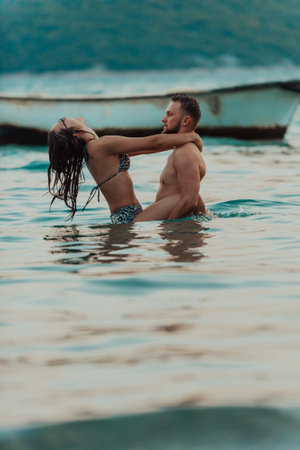 A romantic young couple sharing a passionate kiss amidst the serene beauty of the ocean at sunset.の写真素材