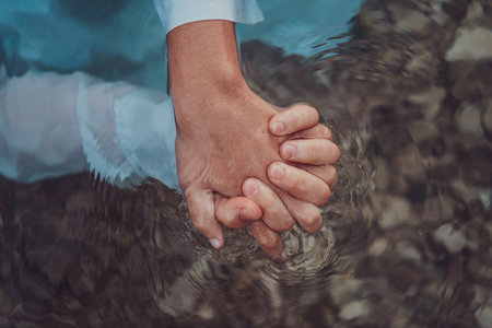 Close up photo the hands of a romantic couple are intimately entwined beneath the waters surface, capturing the tactile and aquatic essence of their love in a sensory embraceの写真素材
