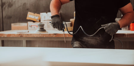 A dedicated worker in the woodworking industry employs compressed air to meticulously clean wooden...