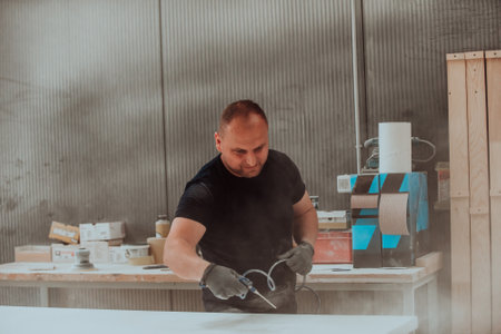 A dedicated worker in the woodworking industry employs compressed air to meticulously clean wooden products in their final stage, exemplifying precision and attention to detail in the craftsmanship of the finished goodsの写真素材