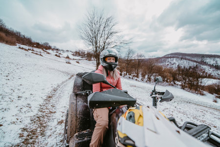 A beautiful blonde woman enjoys the winter wonderland, delighting in a thrilling quad ride through the snow-covered landscape, radiating joy and exhilaration in the midst of the wintry adventureの写真素材