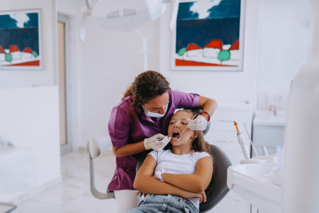 A cheerful girl undergoes a dental examination in a modern pediatric dentistry clinicの写真素材