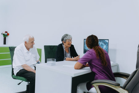 An elderly couple engages in a thoughtful discussion with their dentist about modern denture options in a contemporary dental office settingの写真素材
