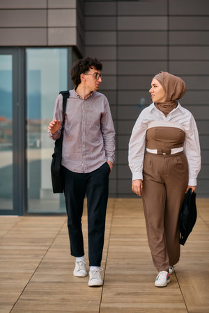 After a day at the office, a business man engages in conversation with his Muslim colleague wearing...