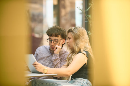 Young Business Duo Strategizing Over Coffee and Tablets