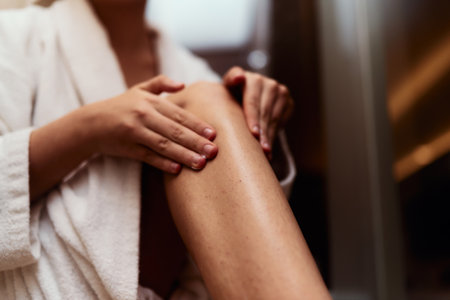 A woman indulges in her self care routine, pampering her skin after a relaxing bath by applying hydrating cream to her legs, embracing the essence of beauty and well beingの写真素材