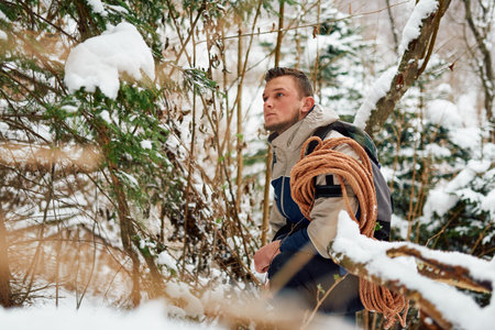 A determined mountaineer sails through a peaceful snow-covered forest, equipped with a rope and a backpack, embodying the spirit of adventure in the heart of winter.の写真素材