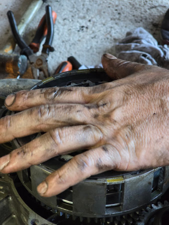 A close up shot of a skilled mechanic with dirty hands diligently repairing engine parts, showcasing the intricate craftsmanship and dedication involved in automotive maintenance.の写真素材