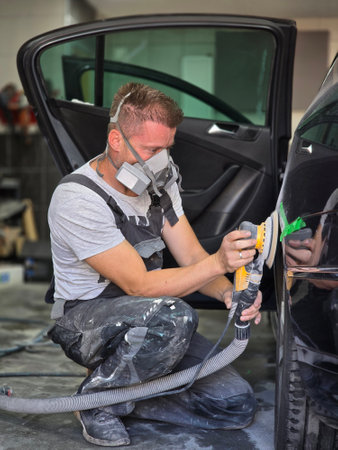 A skilled auto painter meticulously polishing a car to prepare it for painting, showcasing precision and craftsmanship in the workshop.の写真素材