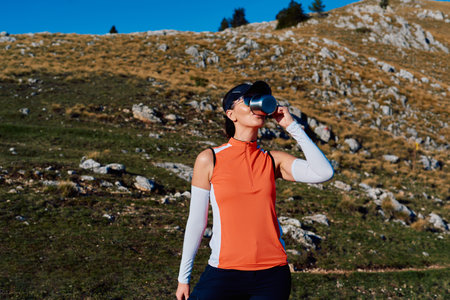 A female hiker enjoys a warm cup of tea while resting after a challenging mountain climb.A woman hiker takes a peaceful break, sipping tea and enjoying the view after a strenuous mountain climbの写真素材