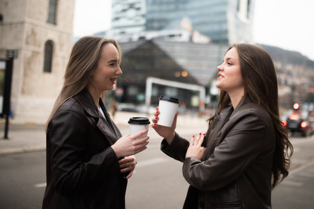 Two Business Women Drinking Coffee on City Streetの写真素材