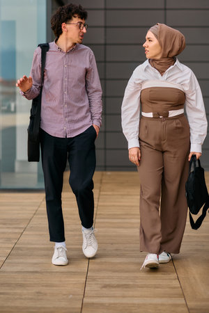 After a day at the office, a business man engages in conversation with his Muslim colleague wearing...