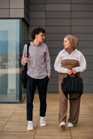 After a day at the office, a business man engages in conversation with his Muslim colleague wearing a hijabの写真素材