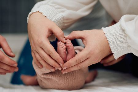 Close up of Hands Forming Heart Shape Around Baby Feetの写真素材
