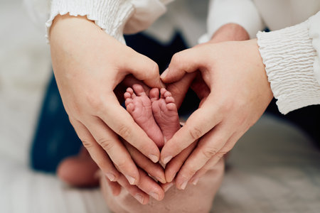 A close up of parents hands forming a heart around their newborns tiny feet, symbolizing love, family, and new beginnings.の写真素材