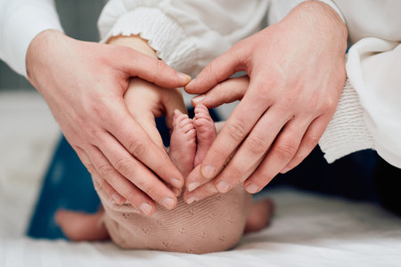 A close up of parents hands forming a heart around their newborns tiny feet, symbolizing love, family, and new beginnings.の写真素材