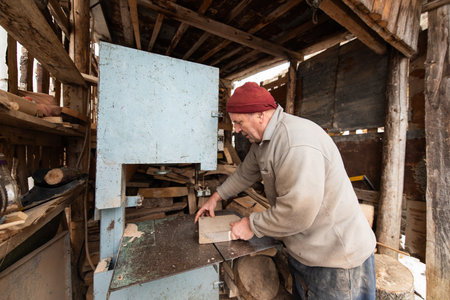 Carpenter Cutting Wood with a Bandsaw in a Rustic Workshop