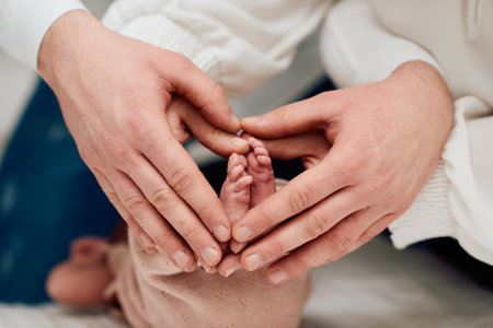A close up of parents hands forming a heart around their newborns tiny feet, symbolizing love, family, and new beginnings.の写真素材