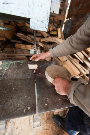 Carpenter Cutting Wood with a Bandsaw in a Rustic Workshop