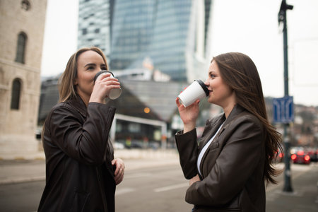 Two Business Women Drinking Coffee on City Streetの写真素材