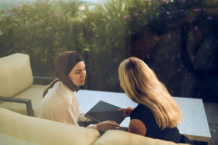 A hijab-wearing woman, a successful real estate business owner, gracefully sells a house to a blonde...
