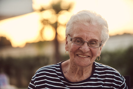 Unfiltered portrait, a real elderly woman sits gracefully in a chair, showcasing the authenticity of aging with wrinkles and a natural faceの写真素材