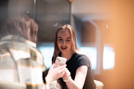 Two young women looking at smartphone in coffee shopの写真素材