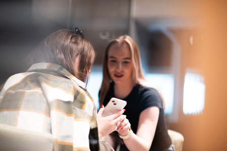 Two young women looking at smartphone in coffee shopの写真素材