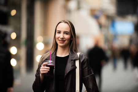 Young woman smiling with juice in city centerの写真素材