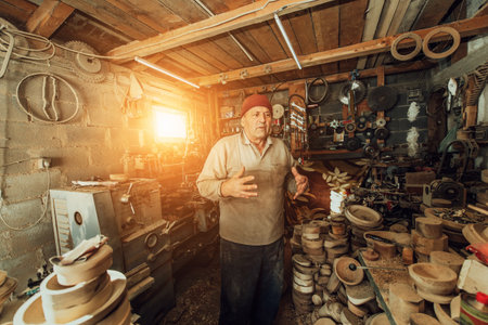 A senior man processing wooden dishes in the workshop in the traditional manual wayの写真素材