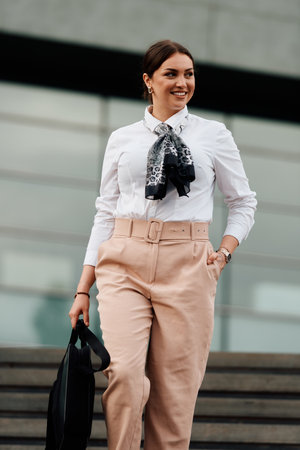 Smiling Latina businesswoman strides confidently through urban streets.