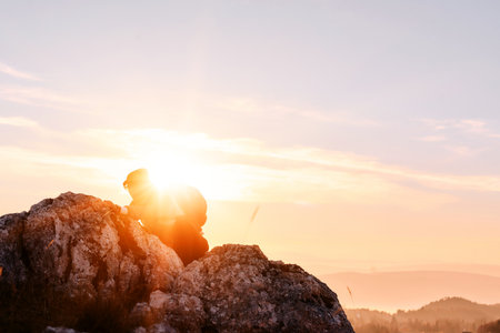 Woman climbing rocky mountain during golden sunrise, symbol of perseverance and challenge in nature