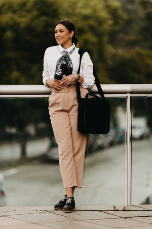 Smiling Latina businesswoman strides confidently through urban streets.の写真素材