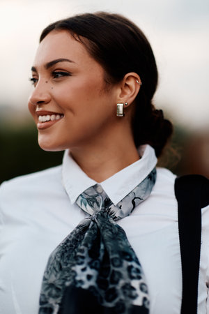 Radiant close up of a beautiful woman beaming with a wide smile in a white shirt, captured outdoors.の写真素材