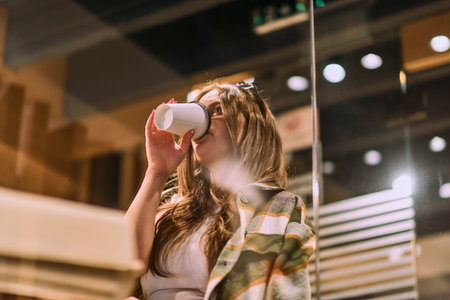 A Moment of Bliss: Beautiful Woman Savors Coffee in Stylish Cafeの写真素材
