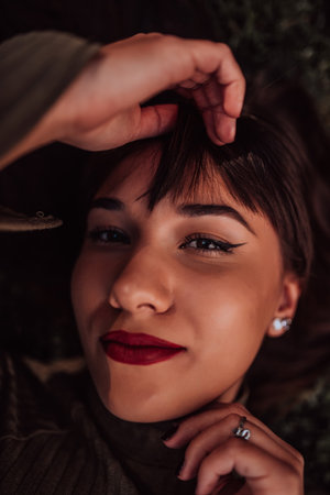A young woman is lying on the grass, showing off her beautiful face with a serene expression. The...