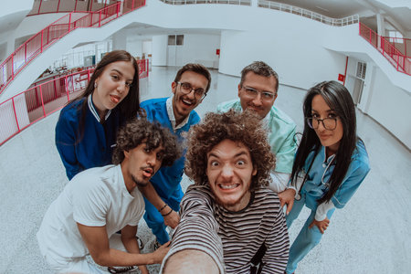 In a modern hospital hallway, a doctor and a medical nurse capture a selfie with a wheelchair patient, radiating joy, inclusivity, and the positive impact of technology in healthcare.の写真素材