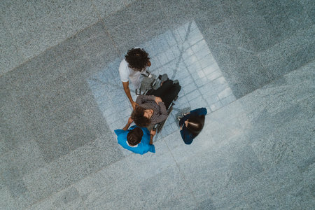 Top view of a group of medics is collaboratively attending to a patient in a wheelchair, demonstrating teamwork and dedication in providing healthcare assistance.の写真素材