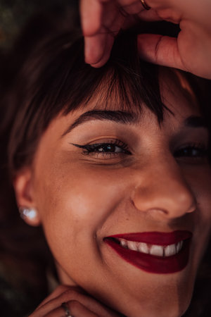 A young woman is lying on the grass, showing off her beautiful face with a serene expression. The lush greenery in the background adds to the peaceful atmosphere of the scene, making it a relaxing and idyllic moment captured in time.の写真素材