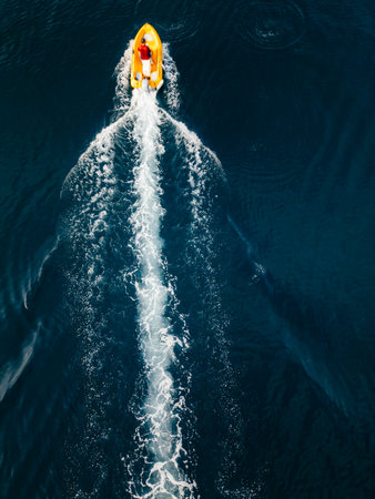 Drone view of a yellow motorboat leaving white water trail on deep blue Adriatic Sea, summer vacation concept in Croatia.の写真素材