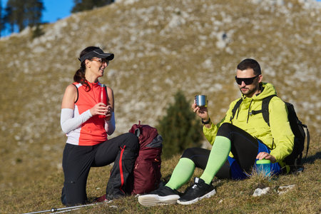 Outdoor hikers taking a break and enjoying drinks on a sunny day in the mountainsの写真素材