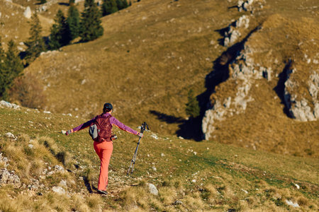 Woman hiking in the mountains enjoying nature on a clear day with trekking poles in handの写真素材