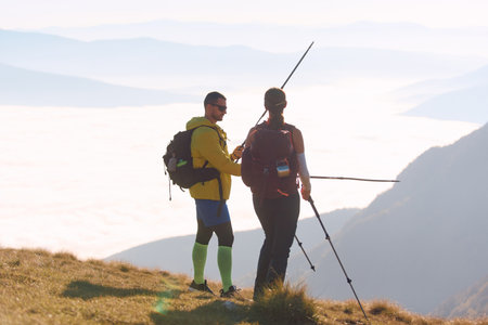 Hiking couple enjoying a stunning view above the clouds on a sunny day