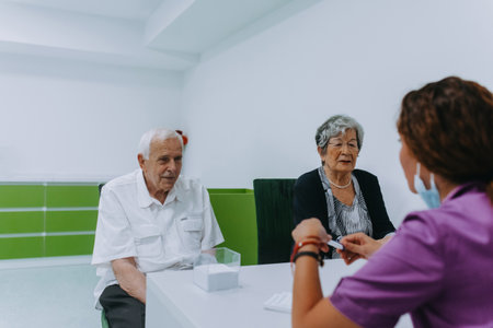 An elderly couple engages in a thoughtful discussion with their dentist about modern denture options in a contemporary dental office settingの写真素材