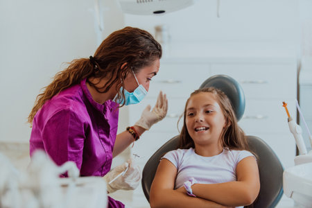 A caring dentist engages in a joyful conversation and entertains a little girl after a dental treatment, creating a child friendly and pleasant atmosphere in the dental office.の写真素材